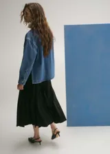 Campera de jean azul con corte recto, cuello camisero, cierre frontal con botones a presión, mangas largas con puños abotonados y dos bolsillos de parche con solapa en el pecho.