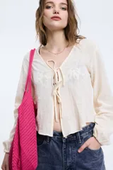 Camisa color crema con escote en V y lazo ajustable, de mangas largas y corte crop.