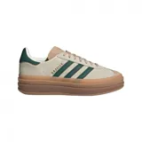 Championes Adidas Gazelle Bold para mujer. Capellada de gamuza color crema con detalles en verde oscuro y suela de goma color caramelo.