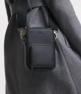 Bolso bandolera porta celular color negro, con correa ajustable y cierres de cremallera.