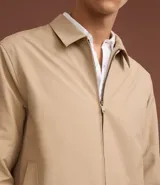 Campera masculina color marrón confeccionada en sarga, con cuello inglés, cierre de cremallera frontal, manga larga y bolsillos con detalles.