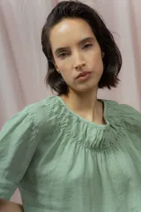 Blusa verde de lino con escote redondo fruncido y mangas cortas.