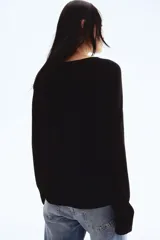 Sweater negro de punto fino, corte holgado, escote redondo y mangas raglán. Tiene cuello, puños y bajo acanalados.
