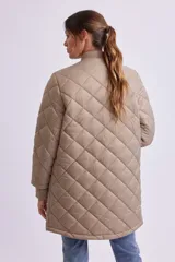 Campera larga acolchada color visón, con cuello redondo, cierre frontal con botones a presión y bolsillos laterales con cierre.