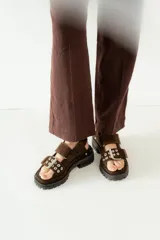 Sandalias marrones con doble tira y hebilla de metal, diseño cómodo y seguro.