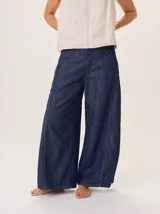 Pantalón ancho de denim azul oscuro, con corte holgado y costuras contrastantes en blanco y rojo.