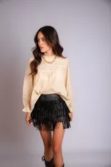 Camisa color crema con cuello alto y mangas largas con volados en los puños. Presenta detalles de crochet y broderie en el frente.