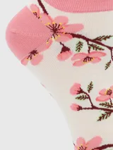 Calcetines cortos de algodón color blanco con estampado de ramas de cerezo en flor rosado. Presentan borde festoneado y talón/punta en color rosa sólido.