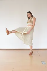 Falda midi color beige de corte evasé, con estructura envolvente y caída fluida. Se ajusta con broches a presión metálicos y cinturón de la misma tela.