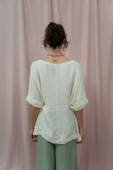 Blusa color crudo de lino, con cuello redondo y mangas 3/4 con dobladillo.