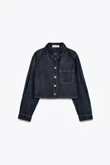 Camisa corta de denim azul oscuro, con cuello solapa, manga larga, bolsillo de parche en el pecho y cierre frontal con botones metálicos.