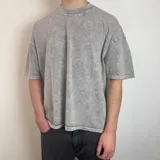 Remera gris con efecto acid wash, corte boxy fit y logo ovalado en la espalda.