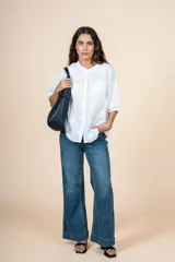 Blusa blanca de algodón con bordado delicado en relieve, corte amplio, botones al frente y cuello redondeado.