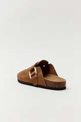 Zuecos negros con base de corcho, puntera cerrada y hebilla dorada decorativa.