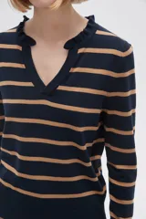 Sweater de punto a rayas horizontales blancas y negras, con cuello en V con volados.