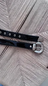 Cinturón negro de cuero gamuzado con hebilla plateada con diseño.