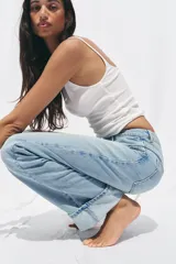 Pantalón de jean celeste de tiro alto, corte recto y largo hasta el tobillo con dobladillo. Tiene cinco bolsillos y cierre frontal cruzado con cremallera y botón.