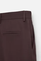 Pantalón de vestir color marrón oscuro, de corte recto, con bolsillos laterales y traseros de doble vivo. Cierre frontal con cremallera y botón.