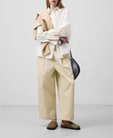 Camisa blanca de algodón con finas rayas verticales. Tiene cuello solapa, cierre con botones, manga larga con puño, bolsillo en el pecho y canesú en la espalda.