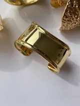 Brazalete metálico dorado de diseño minimalista, confeccionado en aleación.