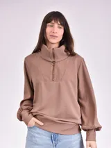Buzo color marrón con cuello alto y cierre de cremallera parcial.