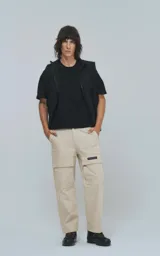Pantalón cargo beige de corte recto con bolsillos laterales y etiqueta con logo en la pierna.