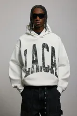 Canguro blanco con capucha forrada cruzada, bolsillo canguro y diseño estampado con letras negras. Corte holgado con hombros caídos y remate acanalado en puños y bajo.