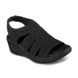 Sandalias Skechers Pier Lite color negro, con capellada tejida y diseño calado. Posee plantilla acolchada de espuma y suela de goma con cuña de 3,8 cm.