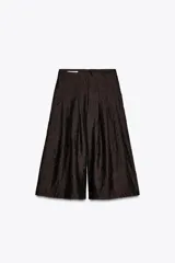 Pantalón culotte color marrón oscuro, de tiro alto con pliegues delanteros y tejido semitransparente efecto arrugado. Tiene forro interior y cierre lateral con cremallera oculta.