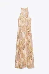 Vestido midi de cuello halter con estampado paisley en tonos beige, amarillo y marrón. Tiene lazada en la espalda, cintura elástica y falda plisada. Cierre trasero con cremallera oculta, abertura y botón.