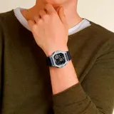 Reloj digital Casio con caja gris, pantalla LCD, correa de resina negra, cronómetro, memoria de 60 vueltas, resistencia al agua de 100 metros, luz LED y batería de 10 años.