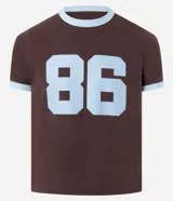 Remera de algodón color marrón con cuello redondo y ribetes en las mangas y cuello en color celeste. Presenta el número "86" estampado en grande en color celeste en el frente.