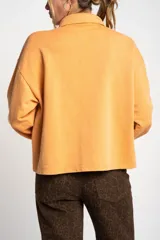 Sweater color naranja con cuello polo y botones, de corte holgado y mangas largas.