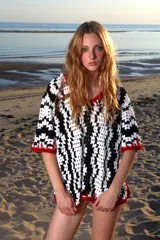 Remera corta tejida a mano en crochet con textura blanca y negra y terminación en pasamanería artesanal con hilado rojo.