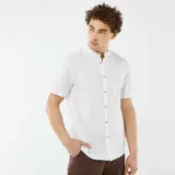 Camisa blanca de lino con cuello mao, manga corta con dobladillo y cierre frontal con botones.