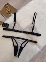 Conjunto de lencería color tostado con detalles en negro, compuesto por un corpiño triangular de encaje con breteles finos y una tanga de encaje con tiras laterales ajustables.