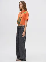 Camisa crop verde con estampado abstracto en tonos naranja y celeste, de mangas cortas y cuello camisero. Confeccionada en viscosa.