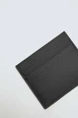 Tarjetero negro con acabado engomado, cuatro ranuras para tarjetas y compartimento central con forro a tono.