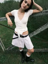 Top blanco de manga corta con escote cruzado y nudo en la cintura. Confeccionado en jersey de algodón.