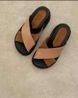 Sandalias Lucy de cuero color beige con tiras cruzadas y suela plana.