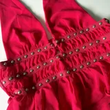 Top rojo con escote halter, confeccionado en microtul con detalle de tachas plateadas.