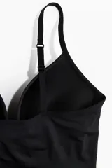 Body colaless negro de punto con efecto push-up, leve efecto moldeador en cintura y caderas, breteles ajustables, copas acolchadas sin aros y refuerzo interior con botones a presión ocultos.