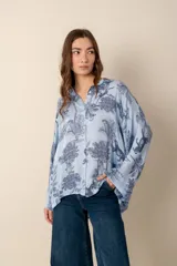 Camisa blanca con estampado de diseño bandana en tonos beige, de corte amplio, con cuello camisero y cierre frontal con botones.