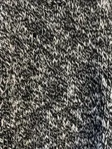 Sweater tejido a mano en lana color gris jaspeado, de calce holgado, con cuello a la base y puños ajustados.