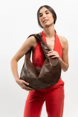 Bolso tipo hobo de cuero color beige, con asa anudada al hombro y cierre superior con cremallera.