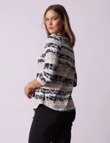 Remera de algodón estampada con rayas horizontales en tonos beige, blanco y negro. Tiene mangas 3/4 y escote a la base.