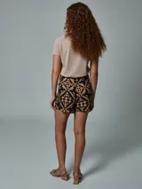 Falda short negra con estampado geométrico en color beige, con detalle de lazo lateral.