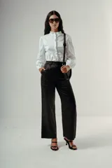 Camisa de manga larga color celeste con finas rayas verticales oscuras. Presenta cuello mao con volados y un detalle de volado vertical en el centro frontal. Las mangas tienen un ligero efecto globo en los hombros.