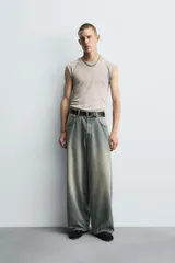 Pantalón de jeans de algodón, corte baggy fit, tiro medio, con efecto lavado en tonos grises y verdes. Presenta cinco bolsillos y cierre frontal con cremallera y botón.