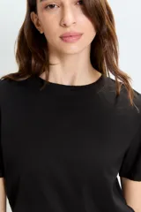 Remera negra de mangas cortas con espalda descubierta y tiras doradas de sostén a la vista.